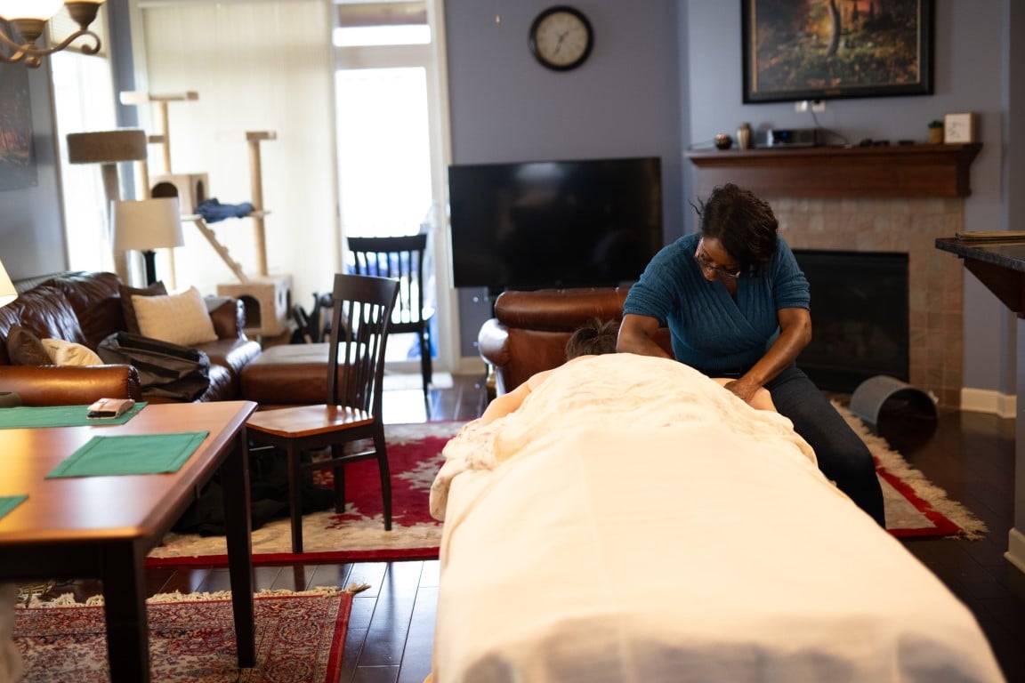 Widlyne setting up a massage in a client's home living room